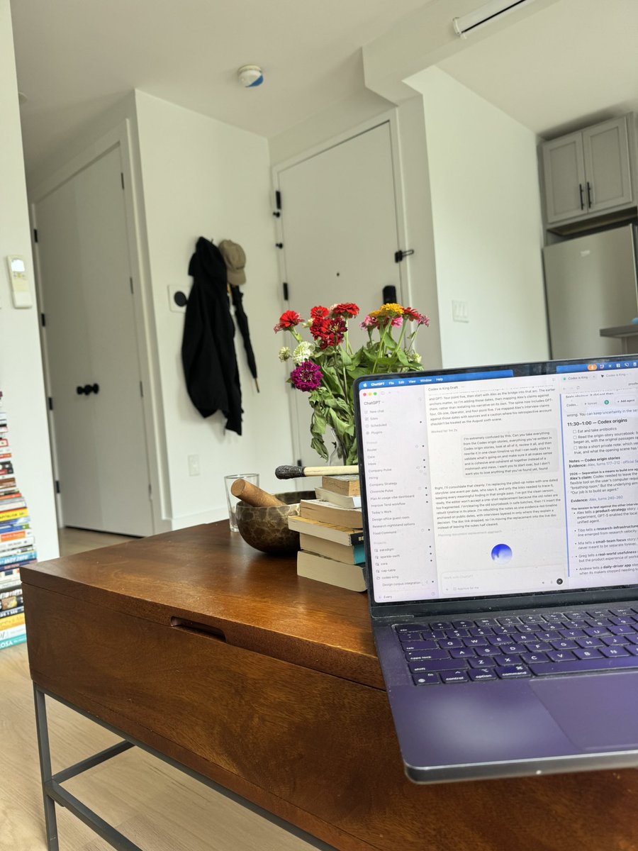 Shipper fotója: nyitott MacBook egy dohányzóasztalon, a képernyőn a ChatGPT felülete a Codex-cikk vázlatával, előtte könyvhalom és virág. Senki nem ül a gép előtt.